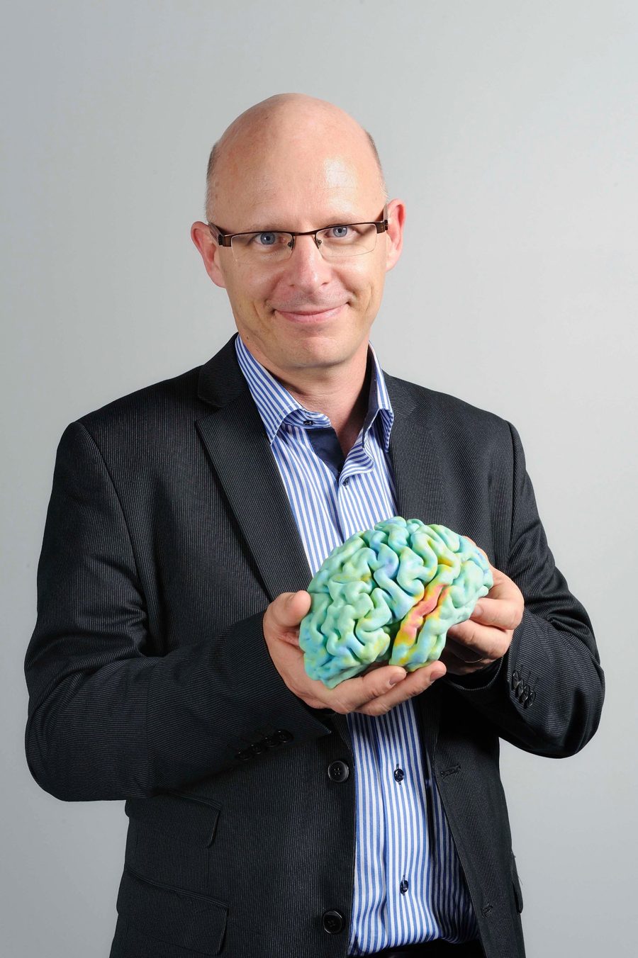 Stanislas Dehaene tenant un modèle de cerveau / Stanislas Dehaene holding a brain model